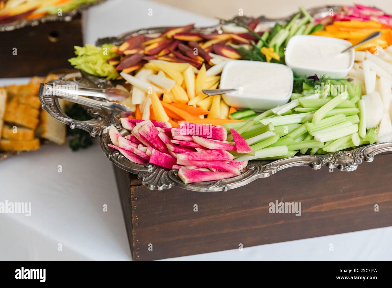 Eine helle und lebendige Präsentation von geschnittenem Obst und Gemüse auf einer dekorierten Platte. Zu den Optionen gehören Sellerie, Karotten, Äpfel und Radieschen, A Stockfoto