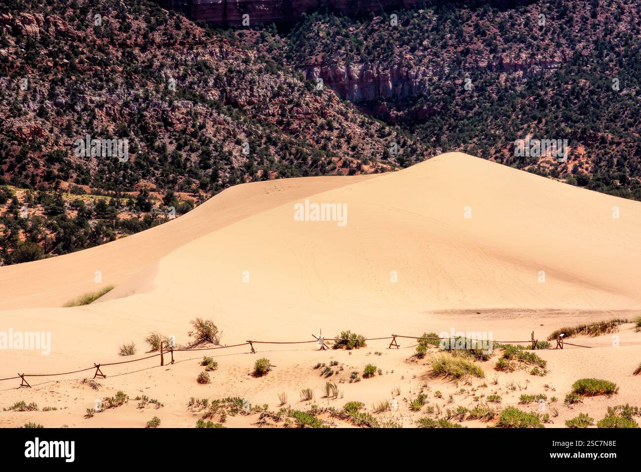 Ein sandiger Hügel mit einem Zaun im Vordergrund. Der Zaun ist aus Holz und befindet sich in der Mitte des Hügels Stockfoto