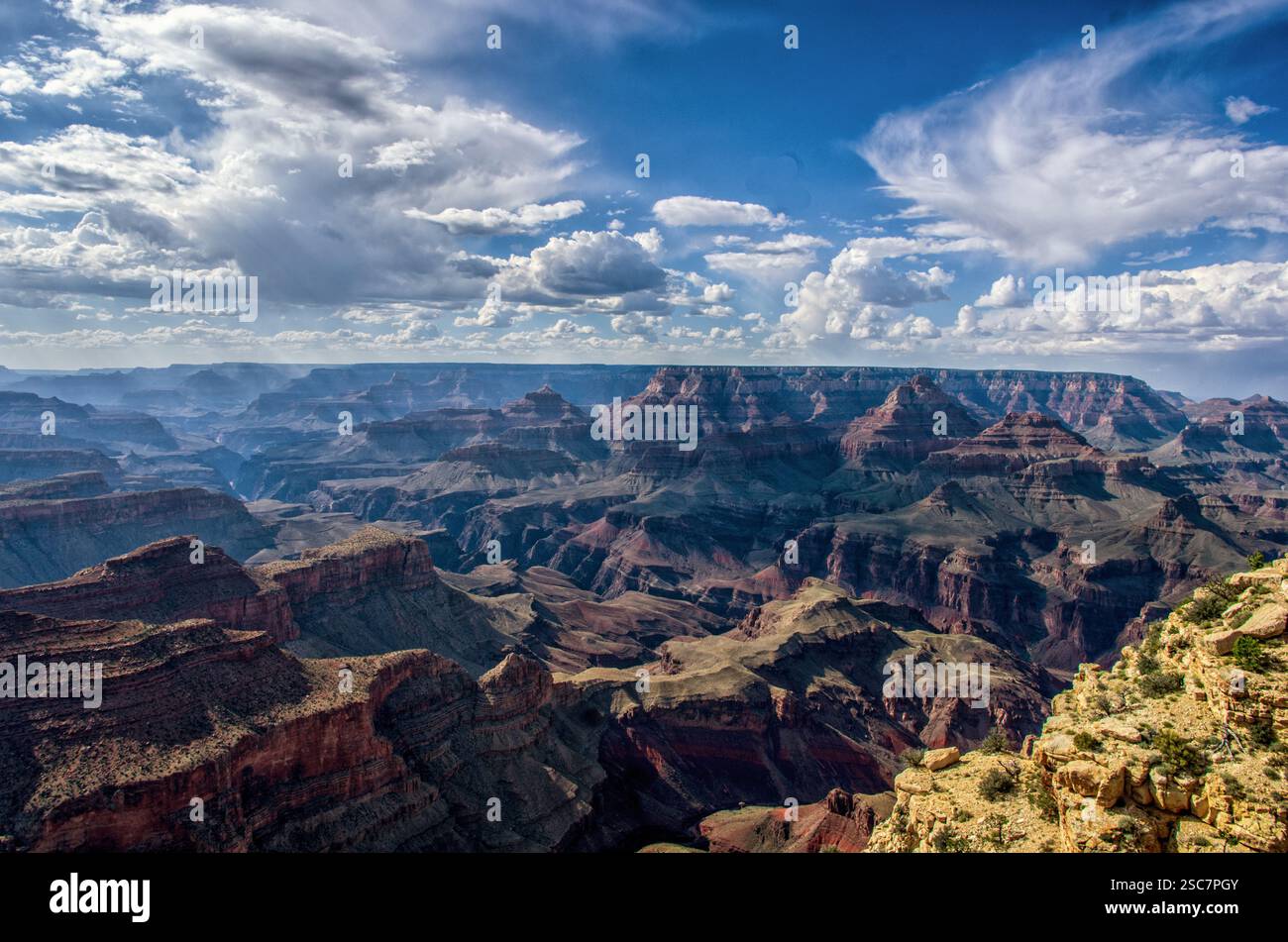 Eine atemberaubende aussicht auf den Grand Canyon mit zerklüfteten Klippen, tiefen Tälern und dramatischen Wolken, die Licht und Schatten über die weite Landschaft werfen. Stockfoto
