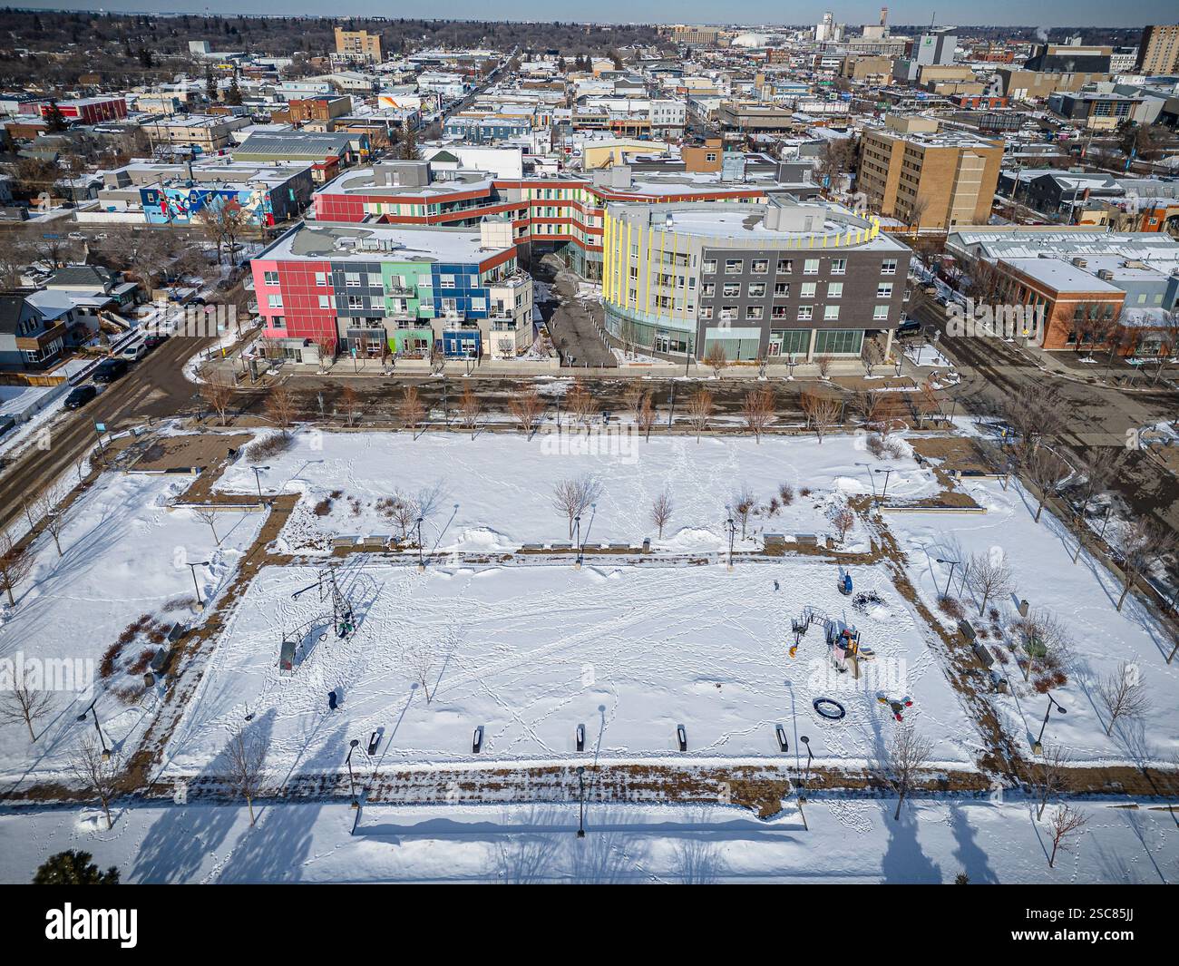 Verschneite Stadtlandschaft mit einem großen leeren Feld in der Mitte. Die Gebäude sind hoch und bunt, und der Schnee bedeckt den Boden Stockfoto