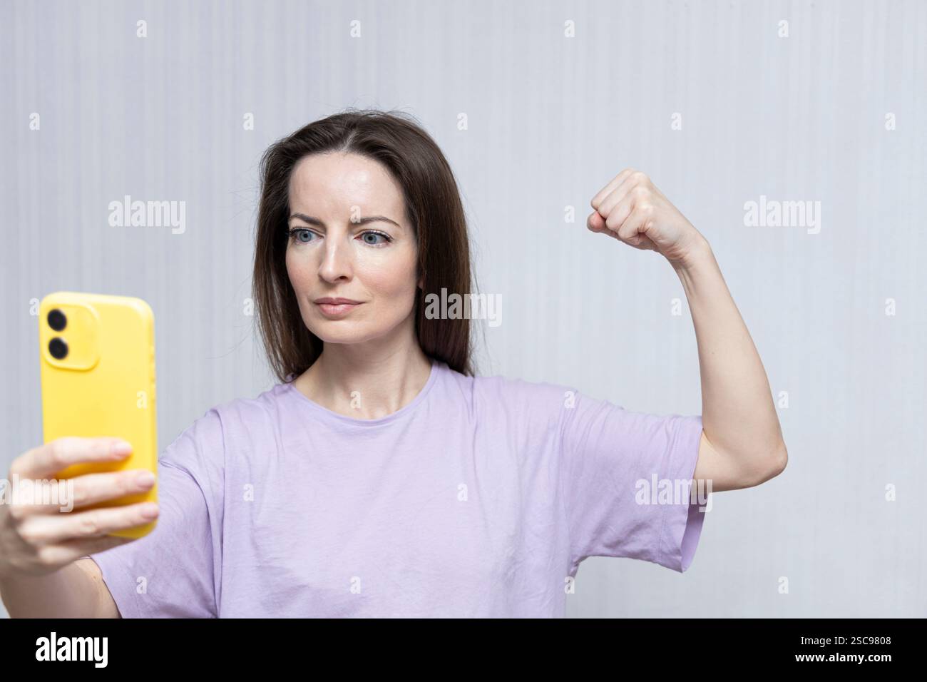 Die Frau zeigte während eines Videoanrufs Kraft, Stärke. Beschleunigen Sie die Aktion IWD2025. AccelerateAction. Internationaler Frauentag. Tag am 8. märz. Stockfoto