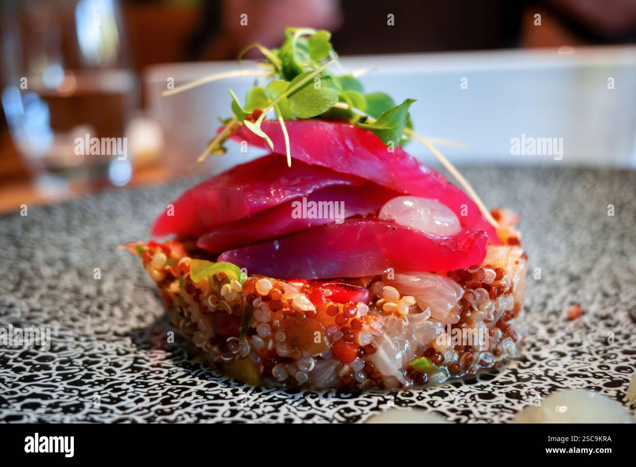 Vorspeise aus mariniertem Bachforellenstück auf Quinoa, Linsen, Zwiebeln und Mango auf Teller, Nahaufnahme. Stockfoto