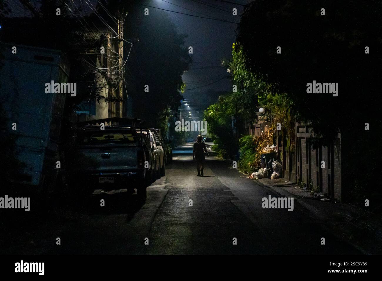 Bangkok, Thailand. Februar 2025. Ein Mann wird bei Sonnenaufgang gesehen, um die kühlste Luft zu bekommen, bevor die starke Verschmutzung und der Verkehr zunimmt, während er an geparkten Autos und Müllhaufen vorbeifährt, auf den Straßen. Bei Sonnenaufgang laufen und joggen die Menschen durch die trüben Straßen, trotz schlechter Luftqualität aufgrund der hohen Luftverschmutzung, die die kühlere Luft optimal nutzt, bevor die Hitze des Tages einsetzt. Pendler auf Motorrädern und Autos navigieren durch den dichten Smog, bevor der Stau beginnt. Quelle: SOPA Images Limited/Alamy Live News Stockfoto