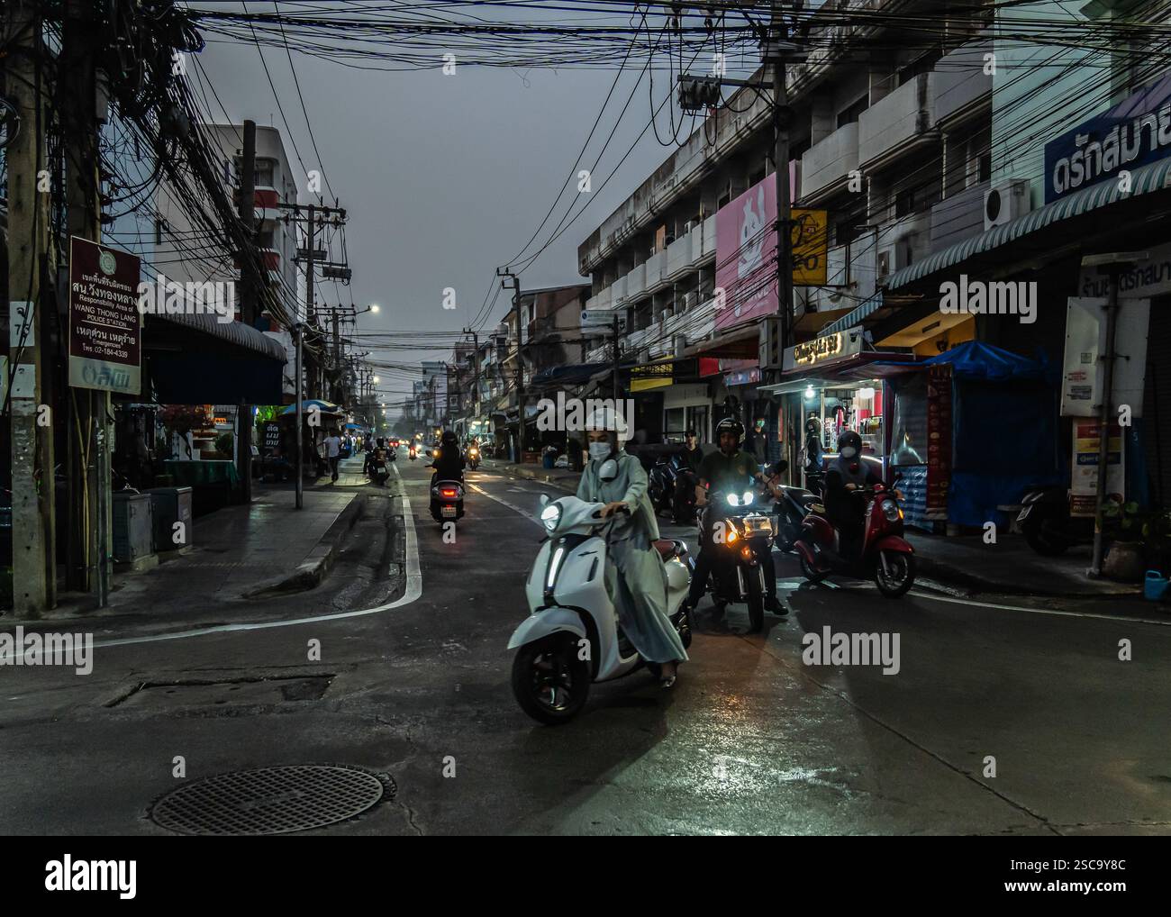 Bangkok, Thailand. Februar 2025. Eine Nahaufnahme einer Pendlerin auf einem Motorrad, die eine Maske trägt, die ausfährt, bevor Staus an einer Straßenkreuzung beginnen. Bei Sonnenaufgang laufen und joggen die Menschen durch die trüben Straßen, trotz schlechter Luftqualität aufgrund der hohen Luftverschmutzung, die die kühlere Luft optimal nutzt, bevor die Hitze des Tages einsetzt. Pendler auf Motorrädern und Autos navigieren durch den dichten Smog, bevor der Stau beginnt. Quelle: SOPA Images Limited/Alamy Live News Stockfoto