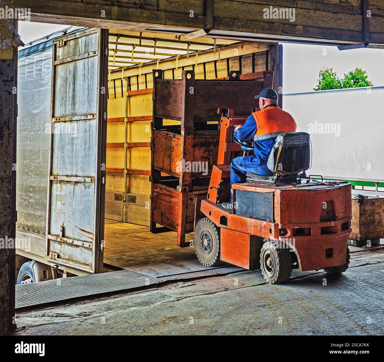 Gabelstaplerfahrer im Overall bei der Arbeit im Lager Stockfoto