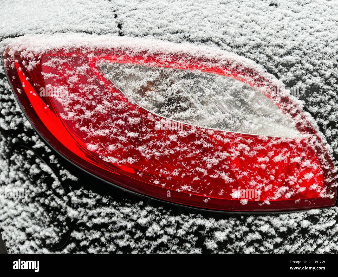 Hintergrundbeleuchtung eines Autos, das im Winter mit Schnee bedeckt ist Stockfoto