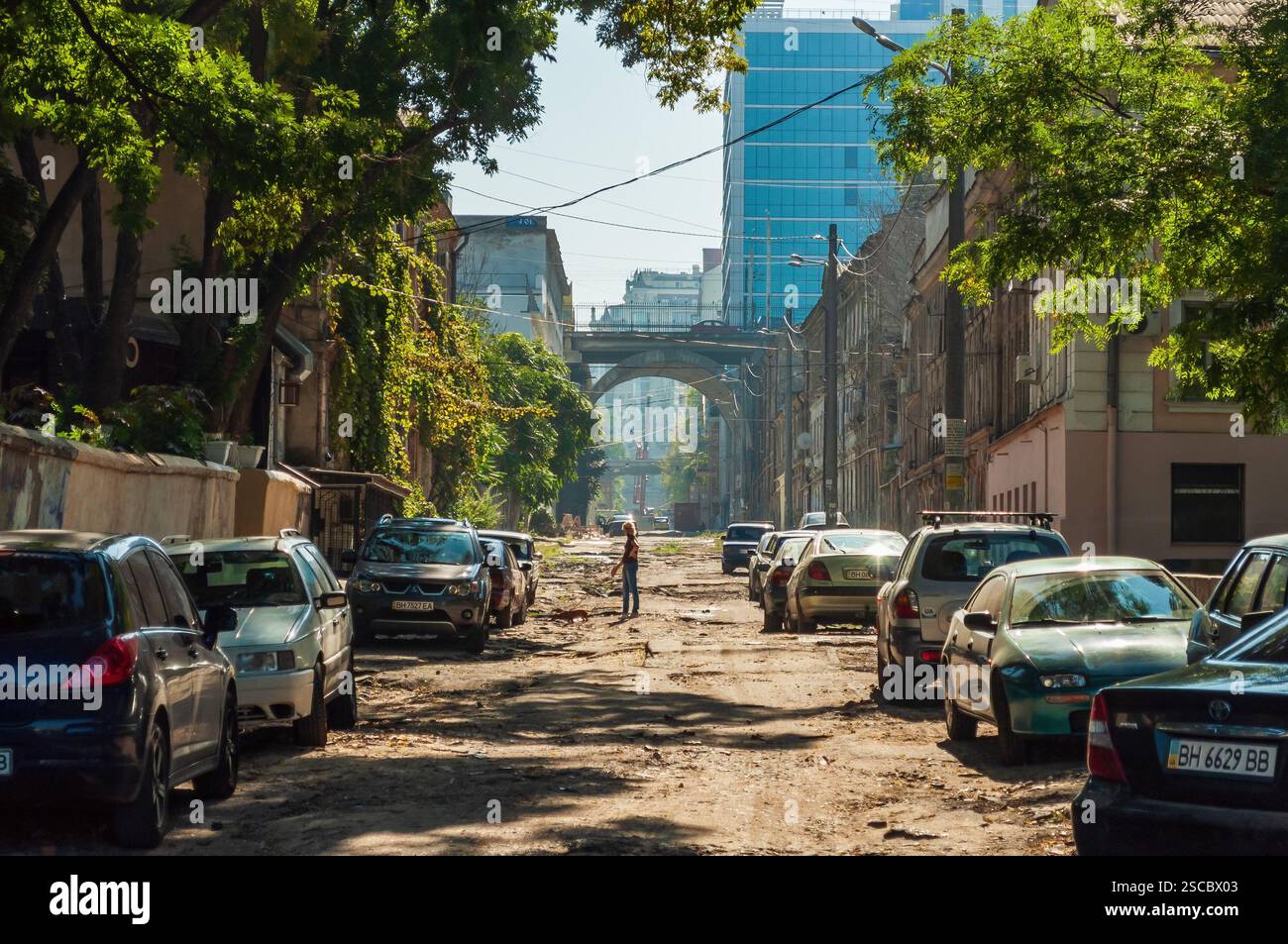Odesa, Ukraine. Januar 2024. Straßenszene mit einer Frau und ihrem Hund vor dem Hintergrund alter Gebäude und moderner Glastürme. Stockfoto