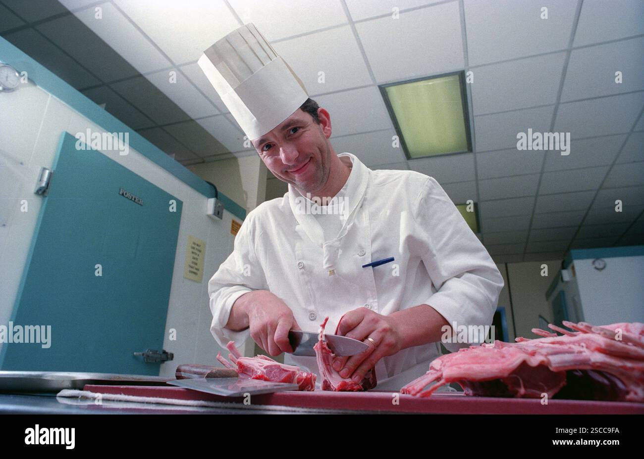 Ein Chefkoch mit traditionellem Haubenhut, der Fleischstücke in einer englischen Hotelküche zubereitet. Der Küchenchef ist Eddie Stevens, der zum Chefkoch im MoatHouse Hotel in Solihull ernannt wurde. Stockfoto