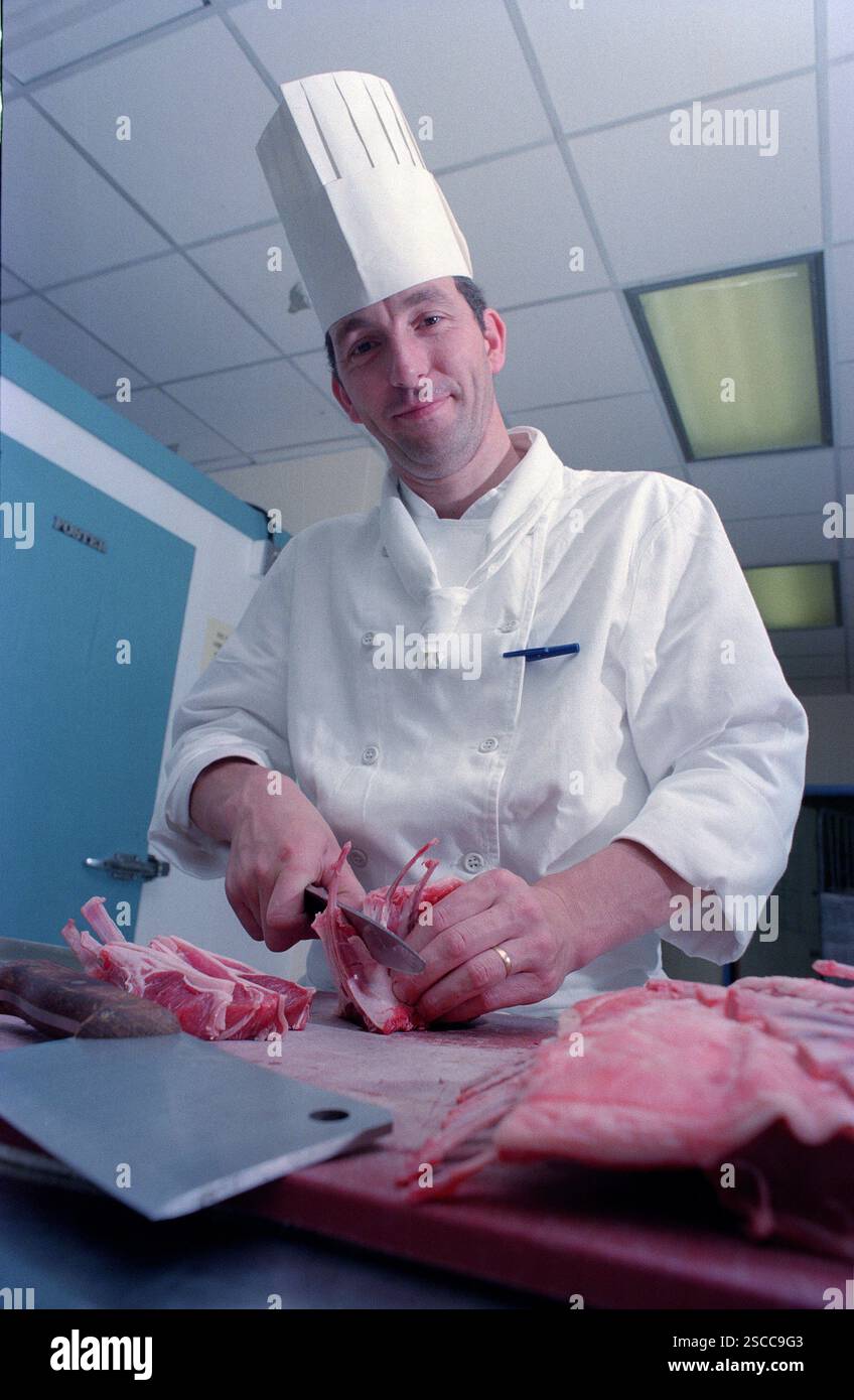 Ein Chefkoch mit traditionellem Haubenhut, der Fleischstücke in einer englischen Hotelküche zubereitet. Der Küchenchef ist Eddie Stevens, der zum Chefkoch im MoatHouse Hotel in Solihull ernannt wurde. Stockfoto