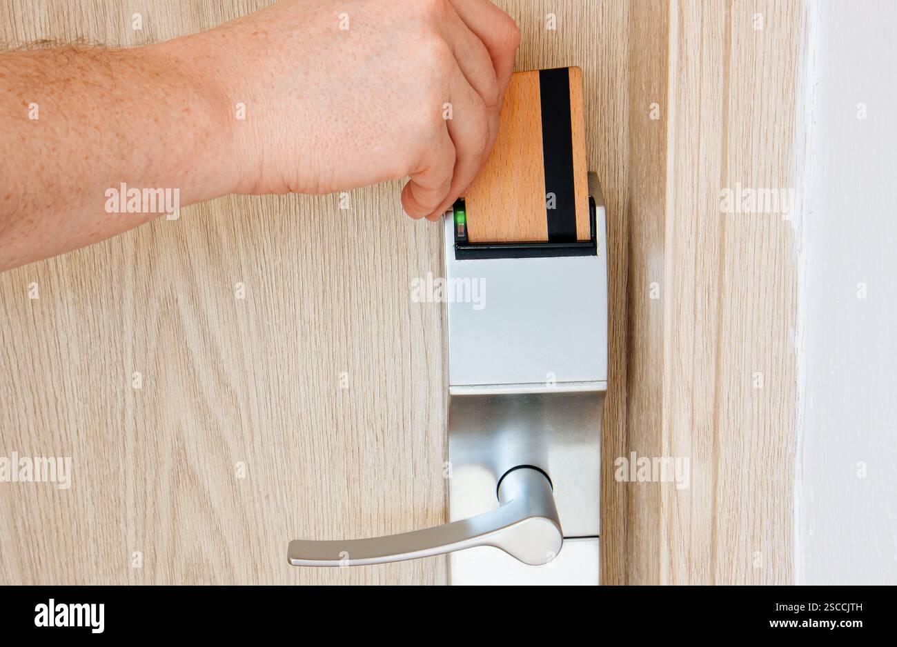 Man Hotelgast mit Holzschlüsselkarte, um die Hotelzimmertür in einem umweltfreundlichen, umweltfreundlichen und nachhaltigen Lifestyle-Hotel zu öffnen. Stockfoto