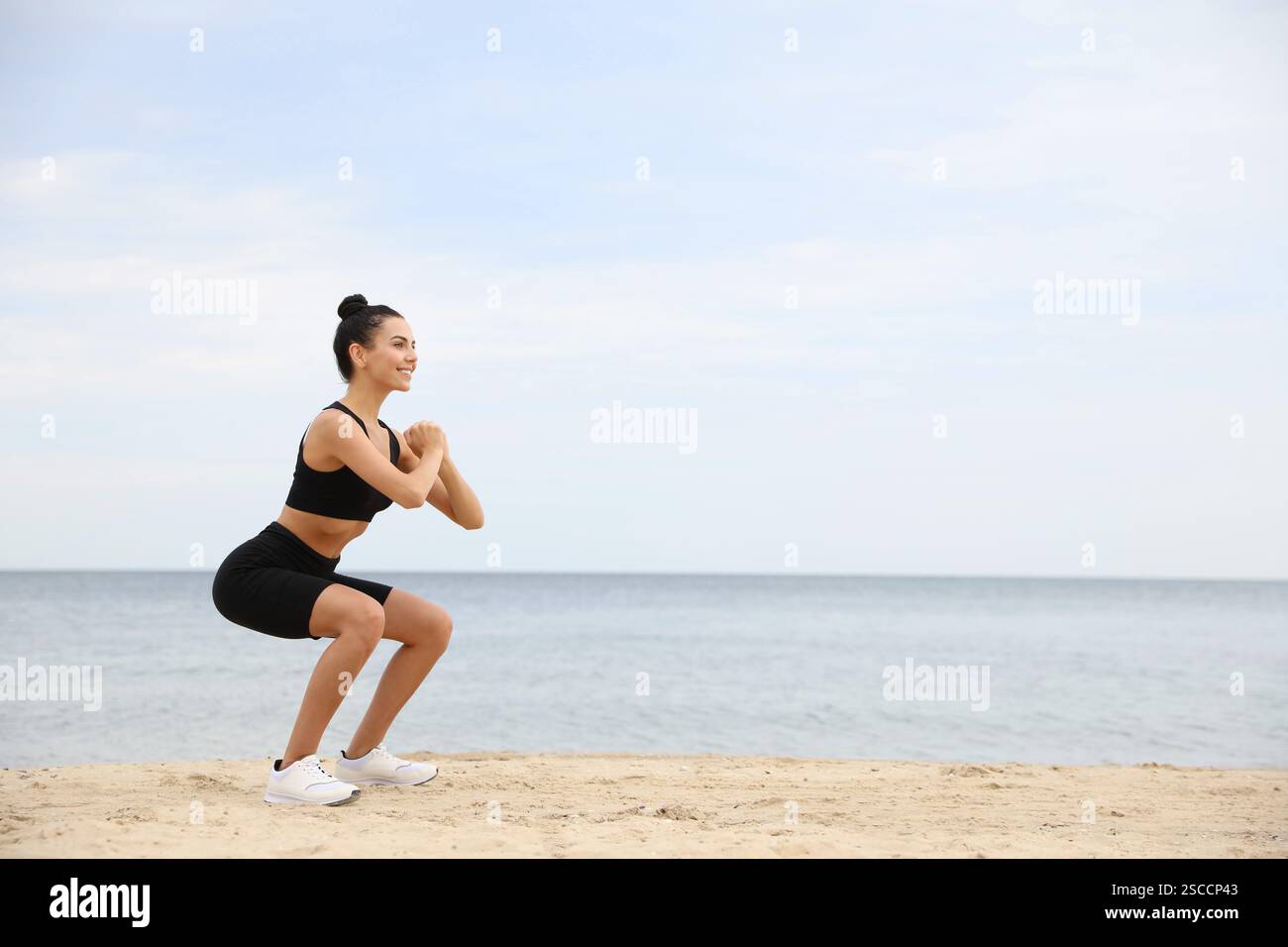 Junge Frau, die am Strand Sport macht, Platz für Text. Körpertraining Stockfoto
