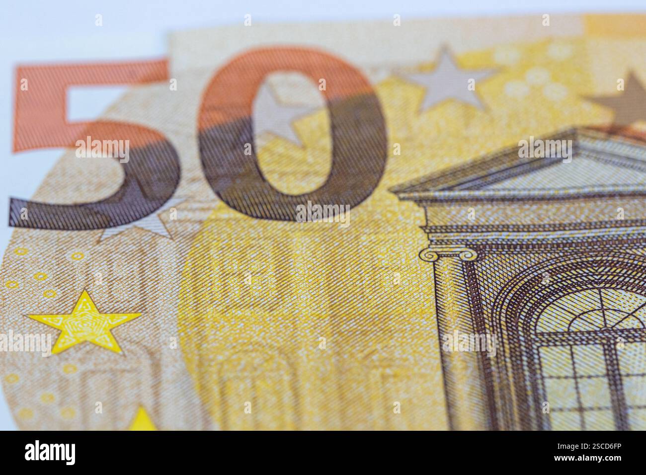 Nahaufnahme einer 50-Euro-Banknote mit Schwerpunkt auf der markanten Zahl „50“ und einem Abschnitt mit klassischer Architektur. Die Farben sind Primarfarben Stockfoto