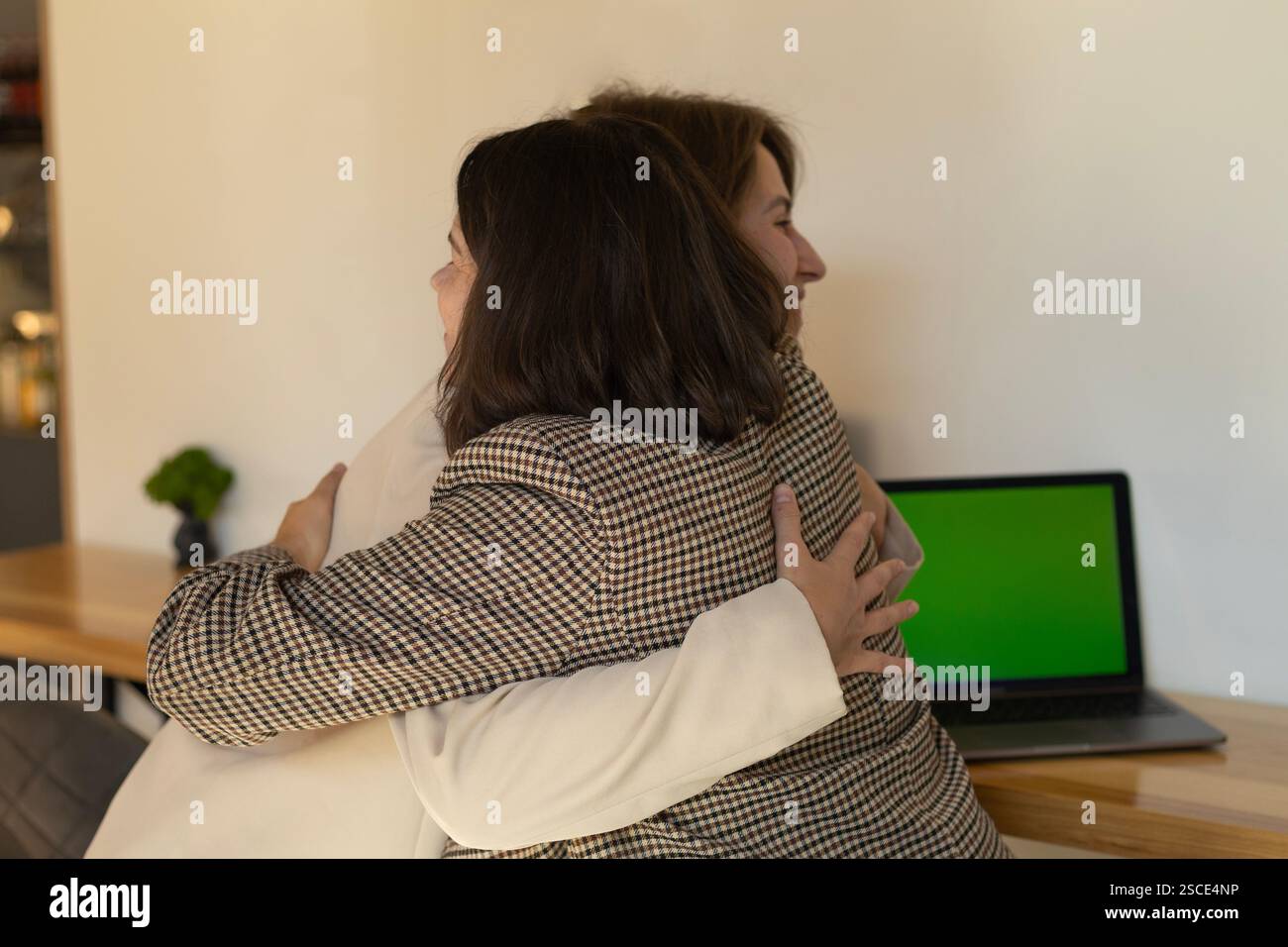 Zwei Frauen sind glücklich und umarmen sich an Laptops in einem Café, ein erfolgreiches Projekt Stockfoto