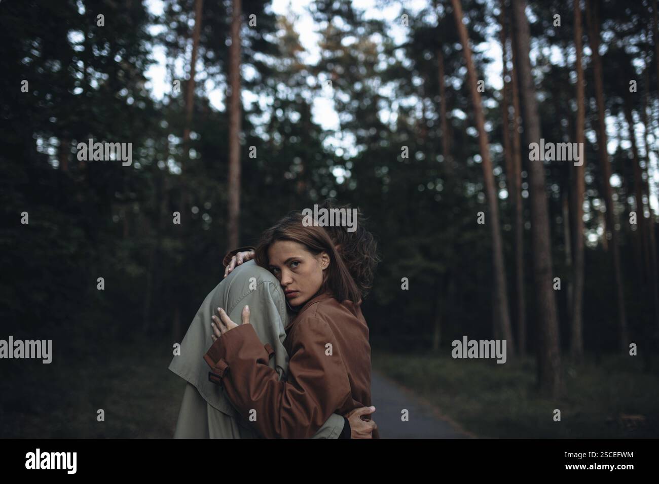 Eine stimmungsvolle Waldszene mit einem Paar, das sich umschließt und emotionale Tiefe vermittelt Stockfoto