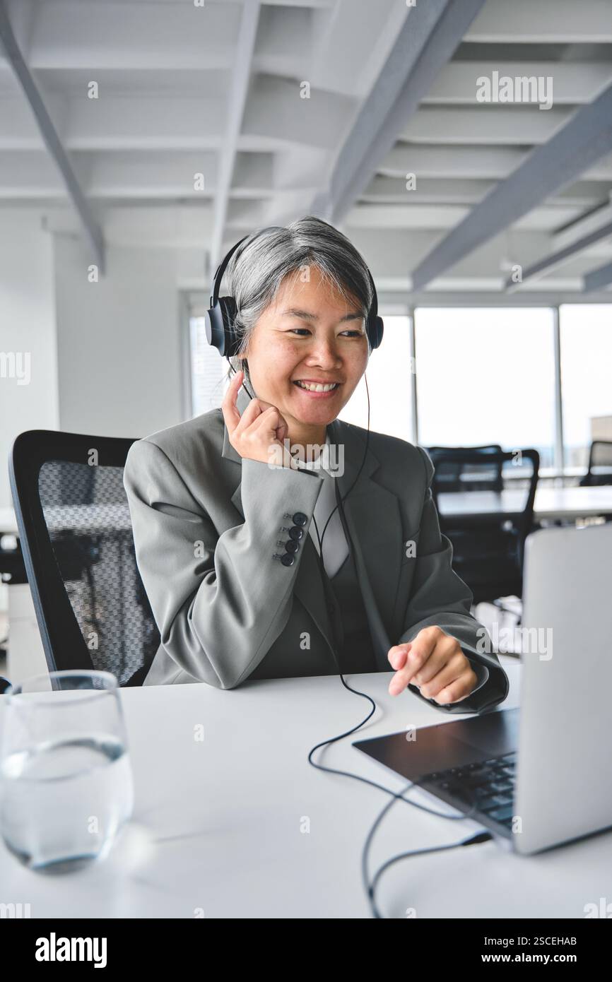 Glückliche ältere asiatische Geschäftsfrau, die ein virtuelles Meeting mit Laptop hat. Stockfoto
