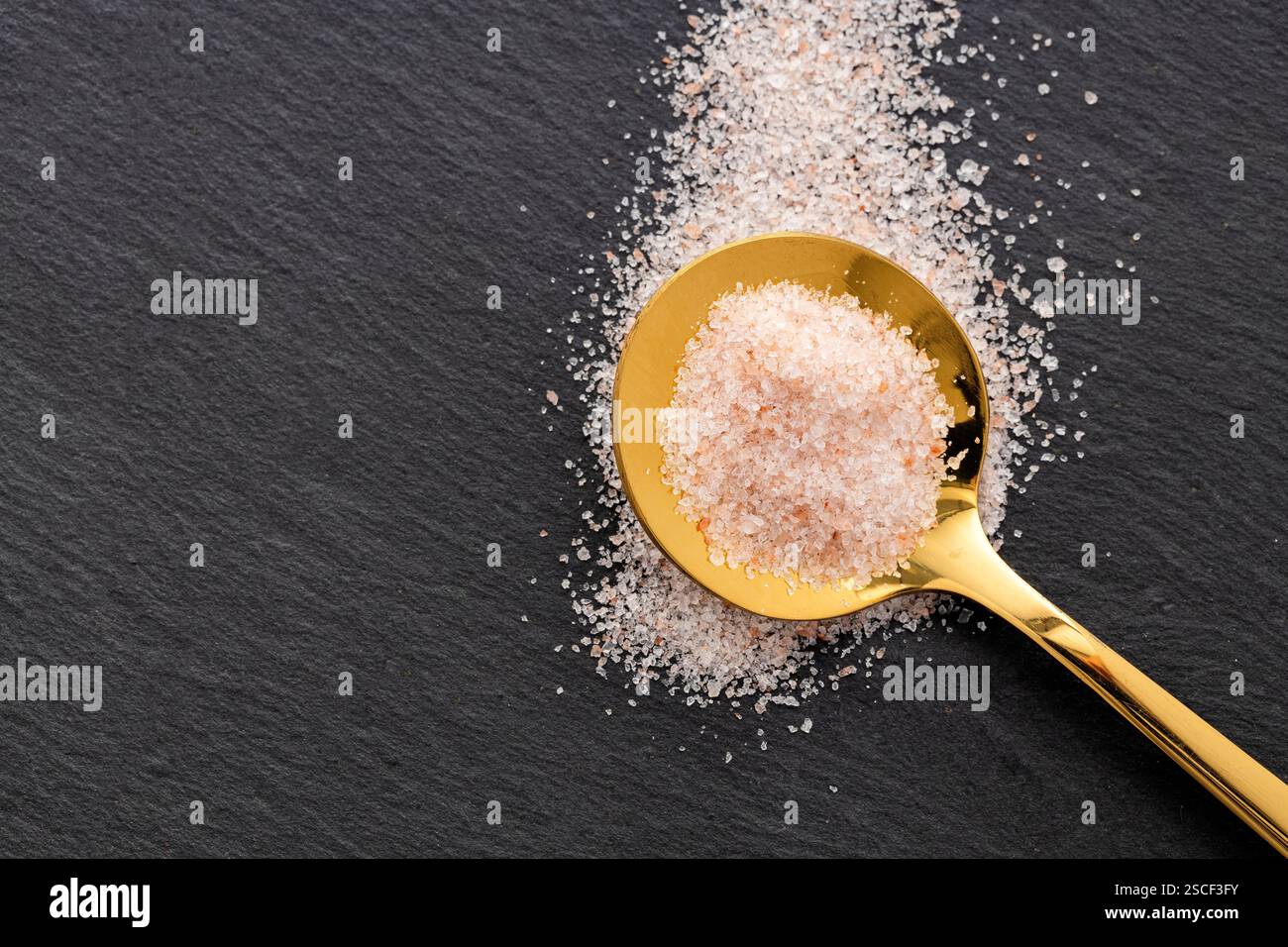Feines rosafarbenes Himalaya-Salz im Löffel - rustikaler Steinhintergrund. Stockfoto