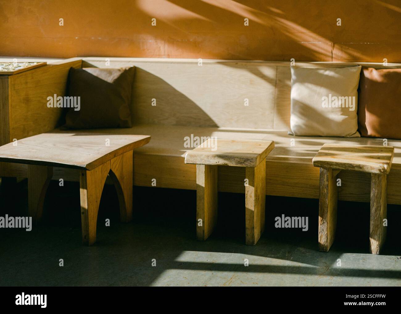 Ein hölzerner Sitzbereich ist schlicht gestaltet und verfügt über mehrere Tische neben einer Couch mit weichen Kissen. Natürliches Licht strömt herein und erzeugt einen Krieg Stockfoto