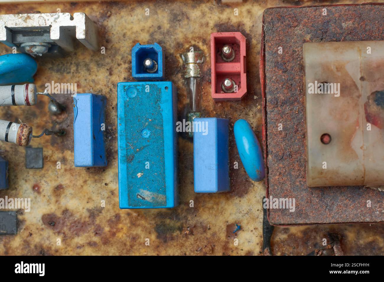 Nahaufnahme beschädigter oder zerlegter Komponenten der Leiterplatte elektronischer Geräte, korrodierter Transformator und Steckverbinder, die von oben entnommen wurden Stockfoto