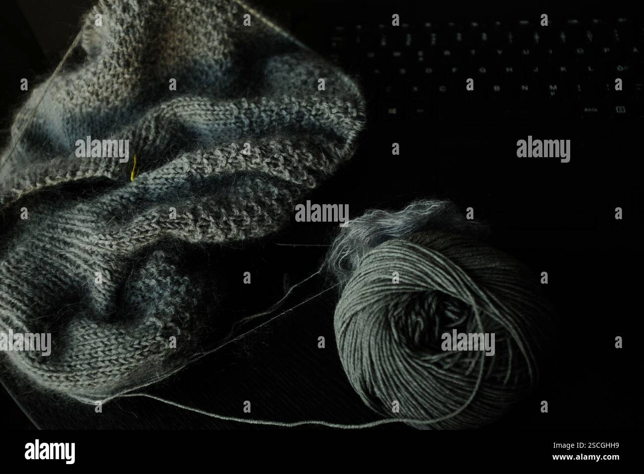 Strickprojekt in grauer Farbe von einem Laptop Stockfoto