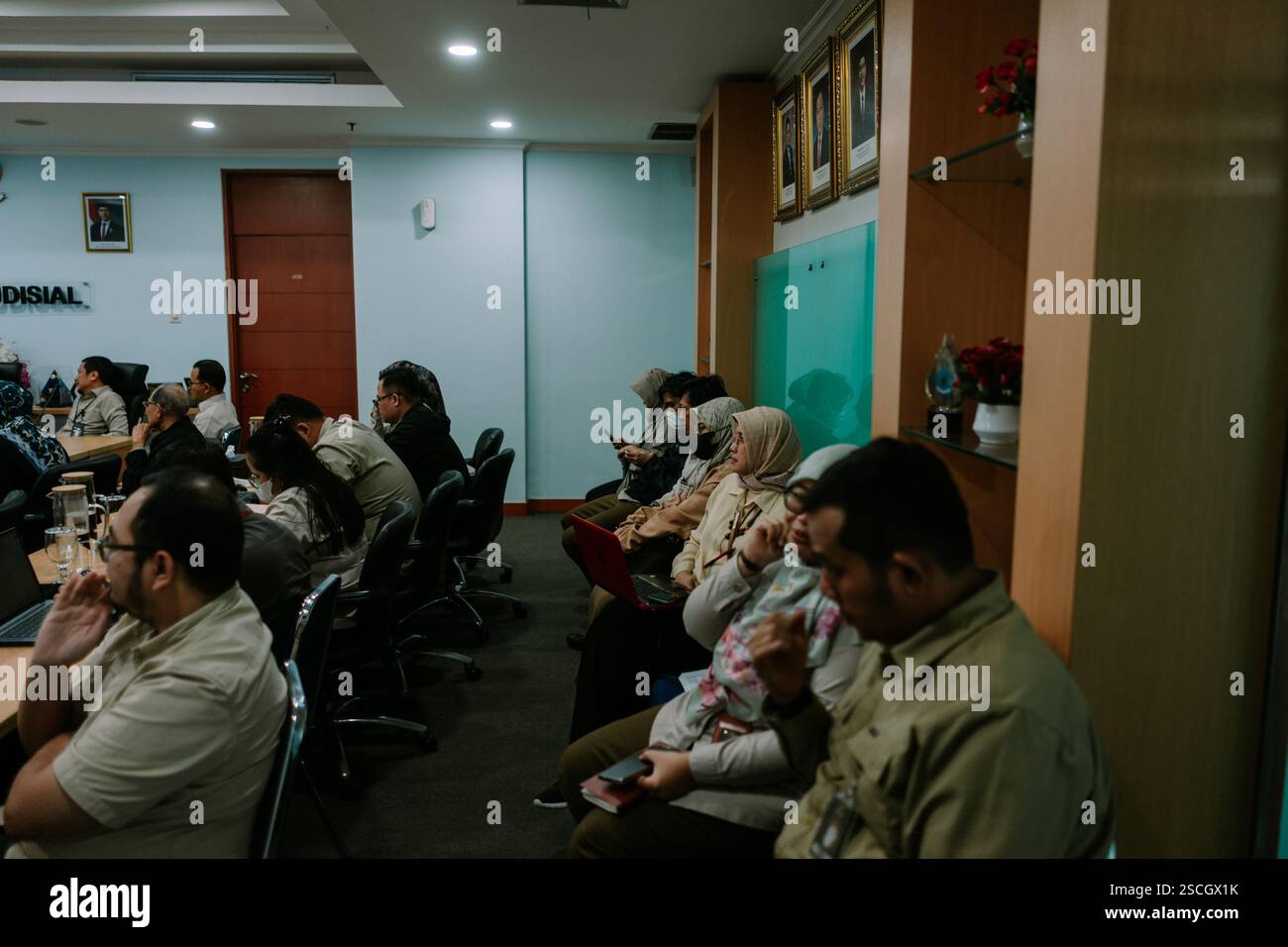 Jakarta, 6. Februar 2025. Gruppe von Personen, die an einer Besprechung in einem formellen Konferenzraum teilnehmen und sich auf eine Präsentation konzentrieren. Stockfoto
