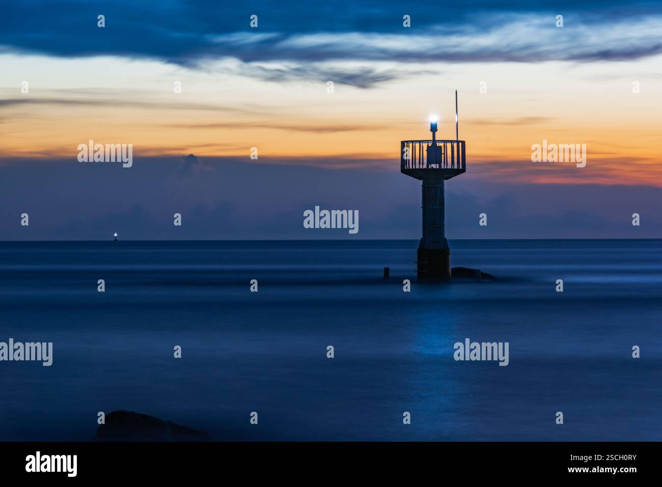 Leuchtturm in der Abenddämmerung mit ruhigem Ozean und farbenfrohem Himmel Stockfoto Leuchtturm in der Abenddämmerung mit ruhigem Ozean und farbenfrohem Himmel Stockfoto