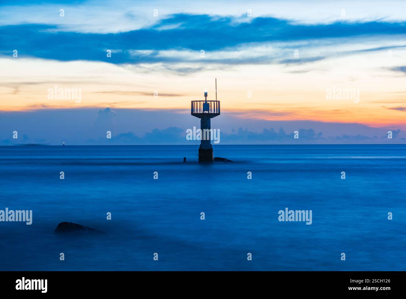 Leuchtturm in der Abenddämmerung mit ruhigem Ozean und farbenfrohem Himmel Stockfoto Leuchtturm in der Abenddämmerung mit ruhigem Ozean und farbenfrohem Himmel Stockfoto