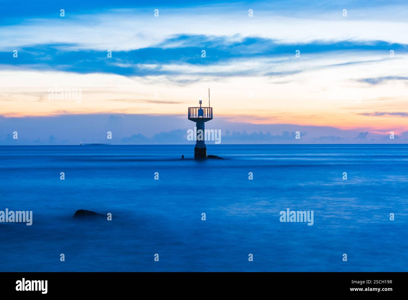 Leuchtturm in der Abenddämmerung mit ruhigem Ozean und farbenfrohem Himmel Stockfoto Leuchtturm in der Abenddämmerung mit ruhigem Ozean und farbenfrohem Himmel Stockfoto