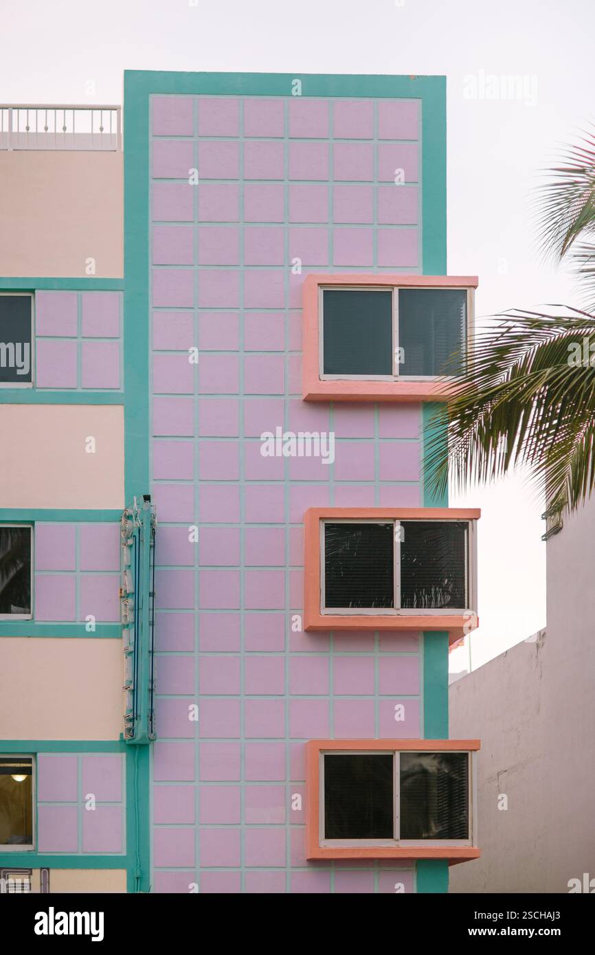 Lebendiges Bild, das ein Miami Beach Art déco-Gebäude mit pastellrosafarbenen und türkisfarbenen Farben zeigt, die sich an kräftigen Fensterrahmen aneinander setzen und die Disti einfangen Stockfoto