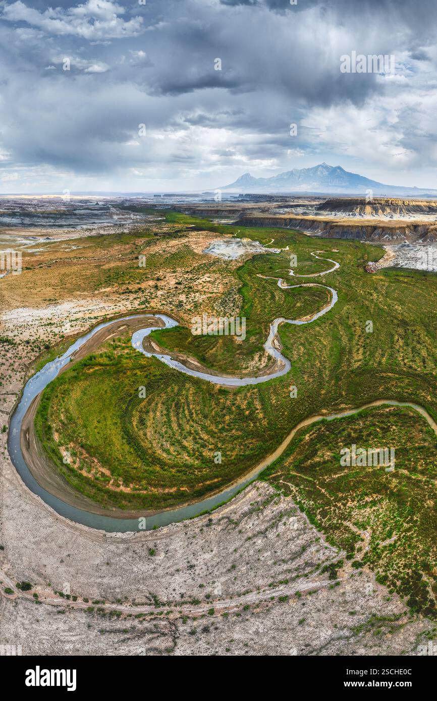 Ein atemberaubendes Drohnenfoto fängt einen sich windenden Fluss ein, der sich durch das zerklüftete Gelände von Hanksville, Utah schlängelt, und zeigt das kontrastreiche ver Stockfoto
