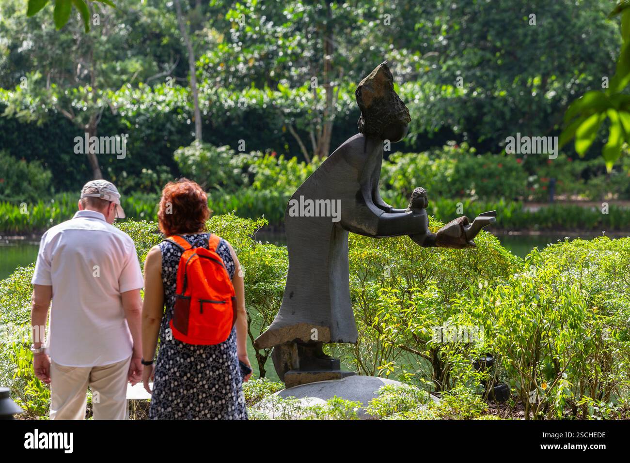 Besucher, die sich die Swing Me Mama Kunstskulptur aus Schaukelstein ansehen, sind auf einem Tourismusausflug in den Botanischen Gärten von Singapur zu Gast. Künstlerische Wertschätzung. Stockfoto