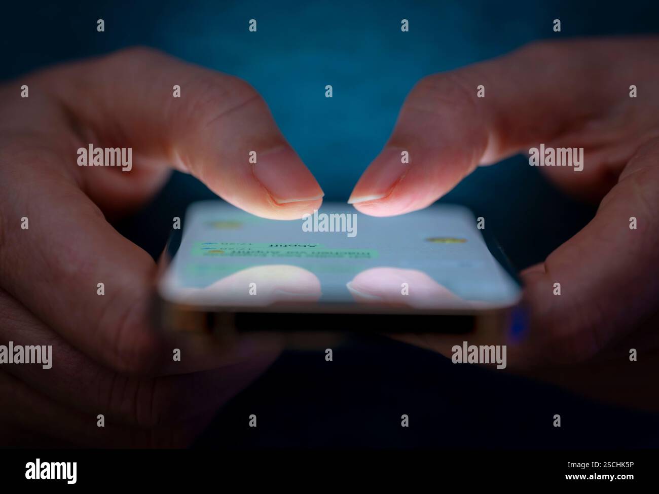 07.02.2025, Thema Smartphone-Nutzung, Frau tippt auf einem Apple iPhone13 Smartphone-Screen SMS. Das Bild zeigt eine Person, die in einer schlecht beleuchteten Umgebung ein Smartphone benutzt. Die Hände des Benutzers sind zu sehen, wie sie das Gerät halten und damit interagieren, wobei auf dem Bildschirm des Smartphones Text angezeigt wird. Die Beleuchtung hebt die Finger des Benutzers und den Bildschirm des Smartphones hervor. 07.02.2025, Smartphone 07.02.2025, Smartphone *** 07 02 2025, Thema Smartphone-Nutzung, Frau, die auf einem Apple iPhone13 Smartphone-Bildschirm SMS tippt das Bild zeigt die usi einer Person Stockfoto