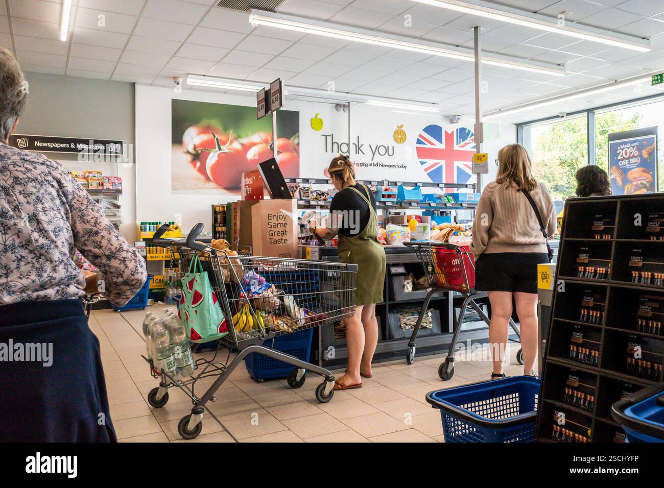 Kunden Kunden Kunden Kunden, die an der Kasse anstehen, um für ihre Waren zu bezahlen, die in einem Lidl-Geschäft in England in Großbritannien einkaufen. Stockfoto