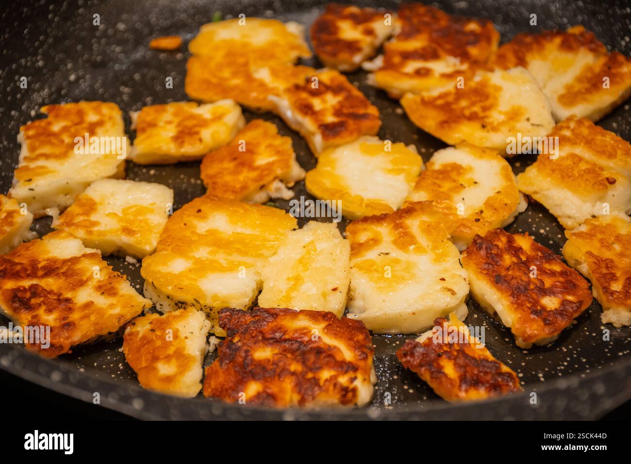 Frittierte mediterrane griechische Zypern haloumi Schaf- oder Ziegenkäse in der Pfanne Pfanne auf dem heimischen Küchenherd. Köstliches Komfortessen ungesund, aber lecker Stockfoto