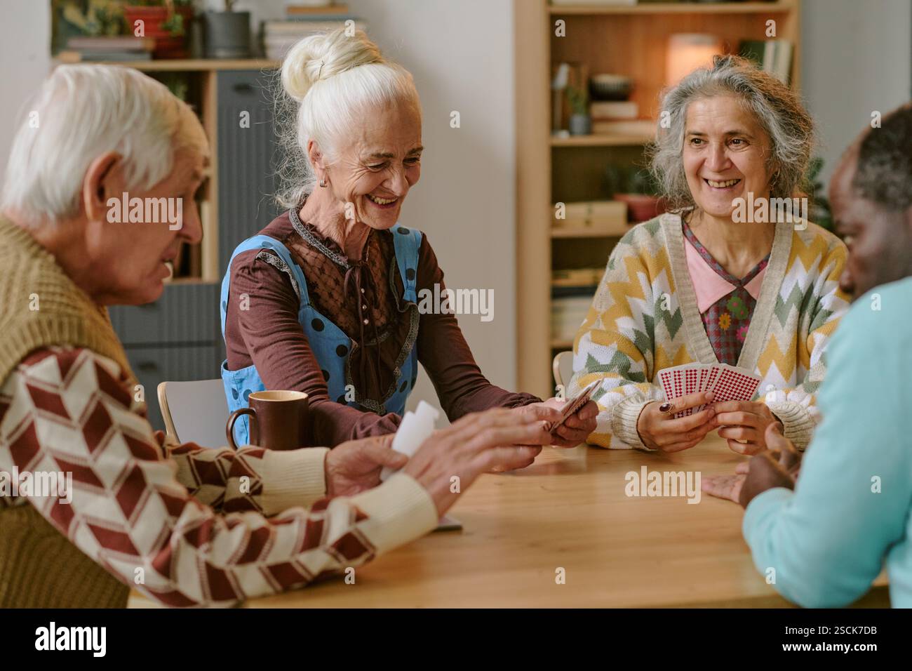 Senioren lächeln und genießen gemeinsam Karten im Pflegeheim Stockfoto