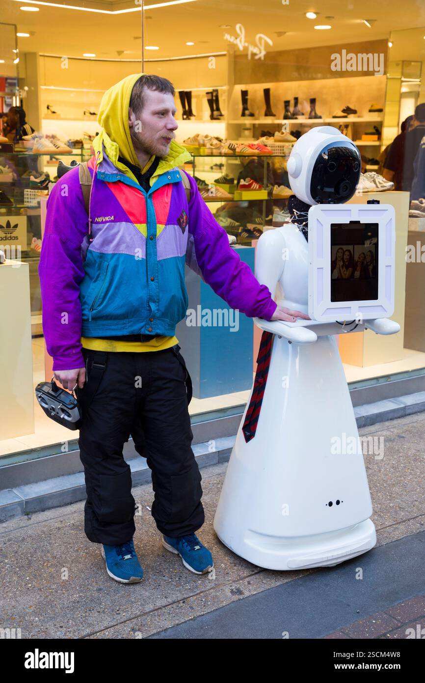 Mann, der mit einem Eva der Roboter steht, Eva autonome Gesichtserkennung spricht Eva's Photo Booth Gerät. Carnaby Street. London. (143) Stockfoto