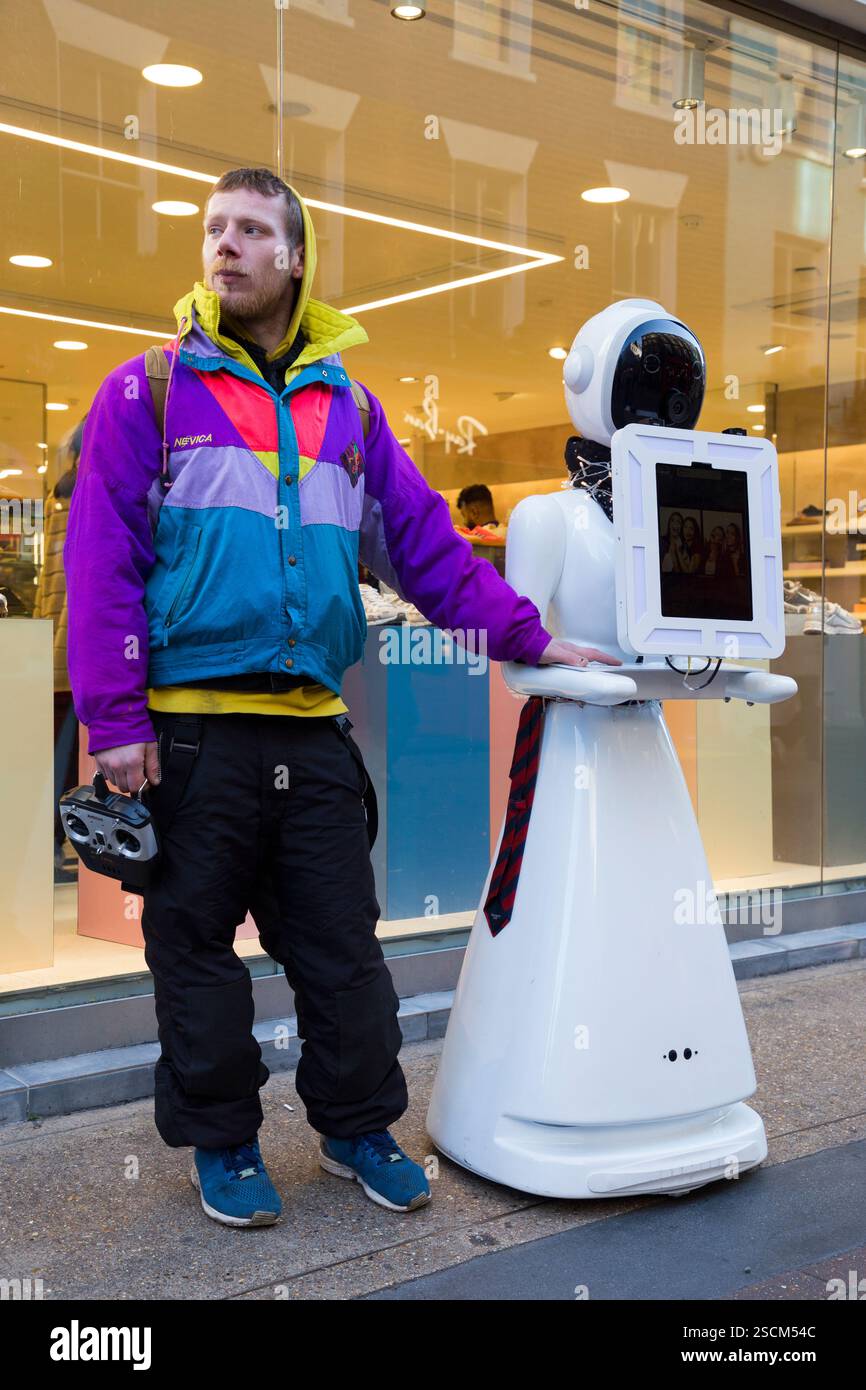 Mann, der mit einem Eva der Roboter steht, Eva autonome Gesichtserkennung spricht Eva's Photo Booth Gerät. Carnaby Street. London. (143) Stockfoto