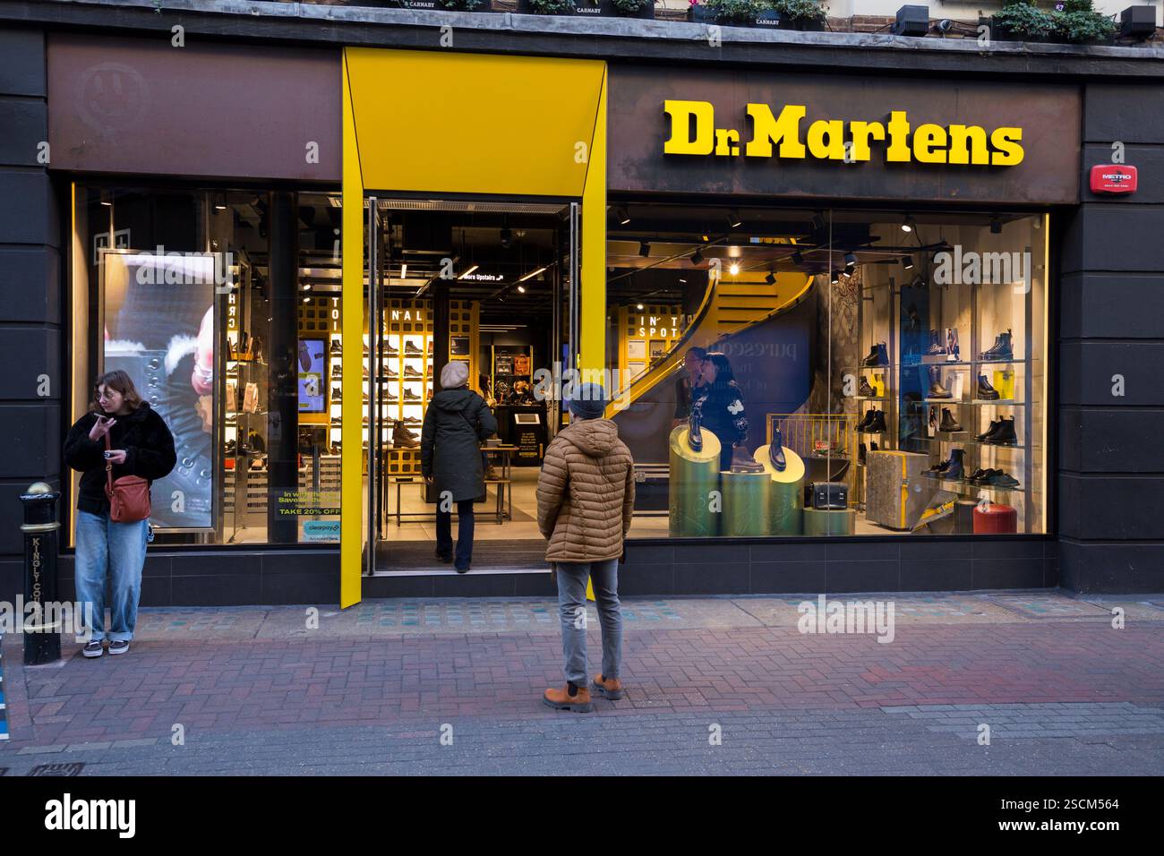 Mann, der steht und auf einen Dr. Martens Schuh- und Schuhladen / Einzelhandelsgeschäft / Einzelhandelsgeschäft / Schaufenster / Schaufenster / vorne in der Carnaby Street blickt. London. (143) Stockfoto