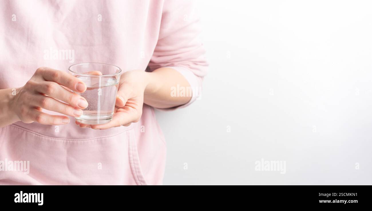Weibliche Hände halten ein klares Glas Wasser. Ein Glas sauberes Mineralwasser in den Händen, gesundes Getränk, Wasserhaushalt, Konzept des Umweltschutzes Stockfoto