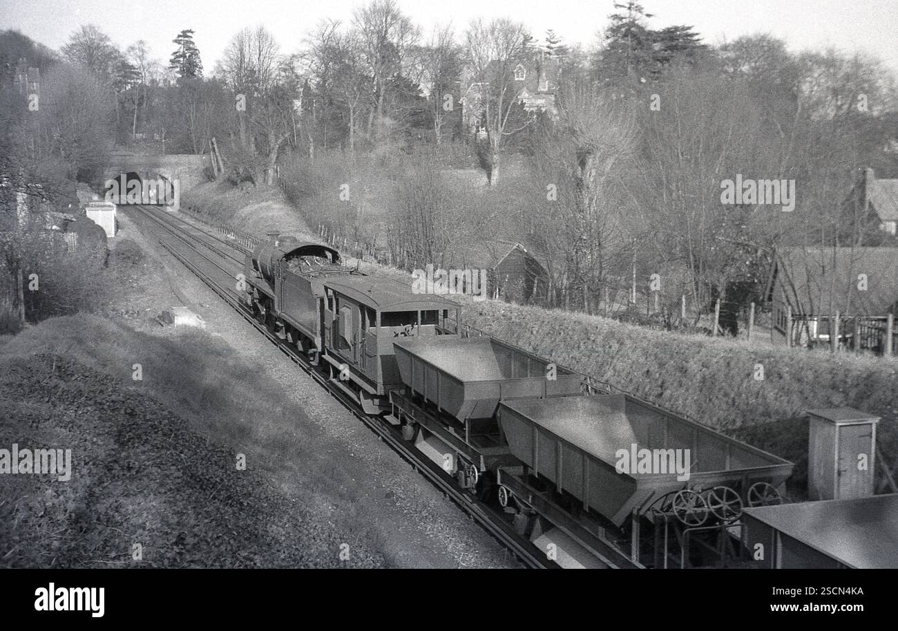 1950er Jahre, historische Dampflokomotive auf Landgleis, die Güterwagen zieht, kurz vor dem Tunnel, England, Großbritannien. Stockfoto