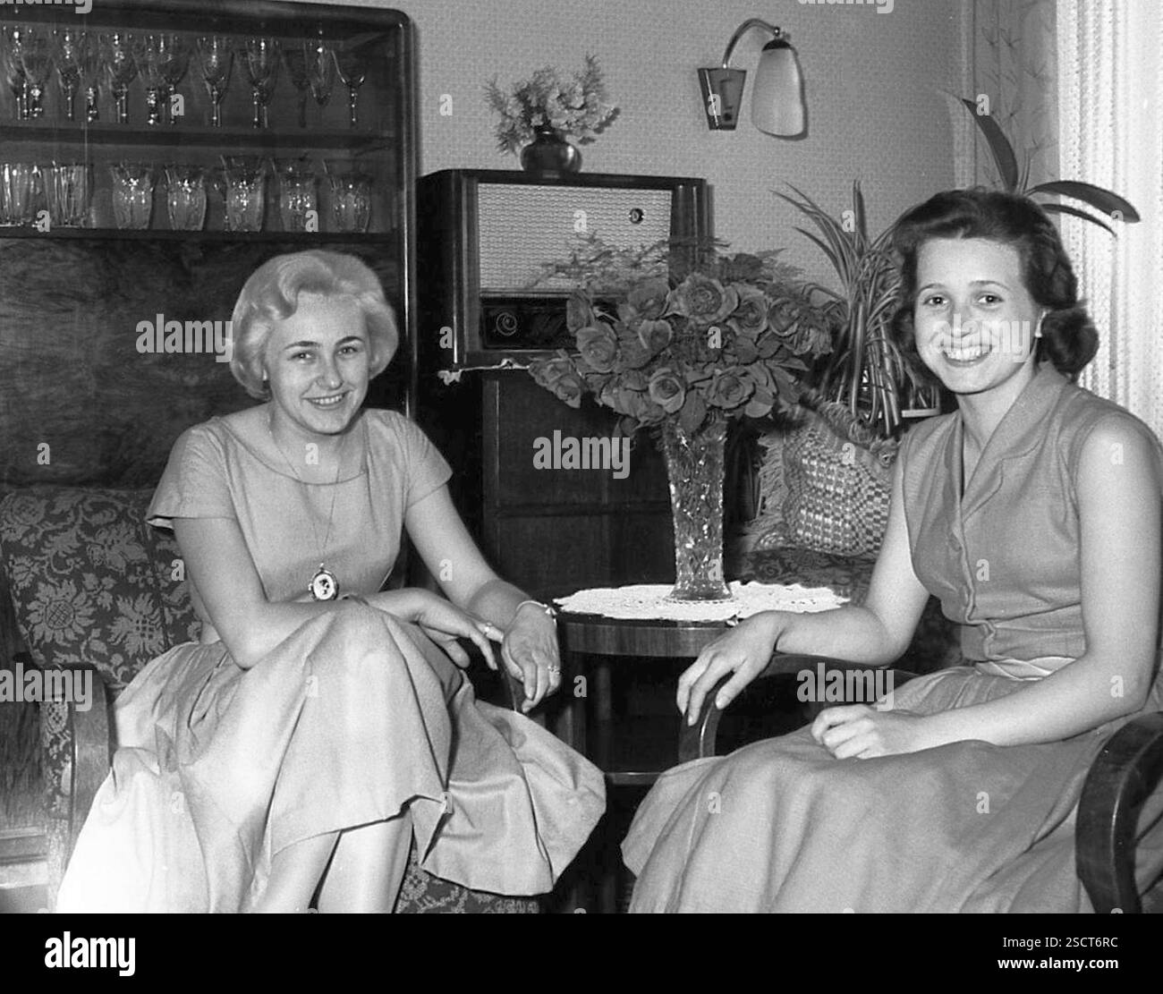 Zwei junge Frauen sitzen an einem Tisch mit roten Rosen, DDR 1957. [Automatisierte Übersetzung] Stockfoto
