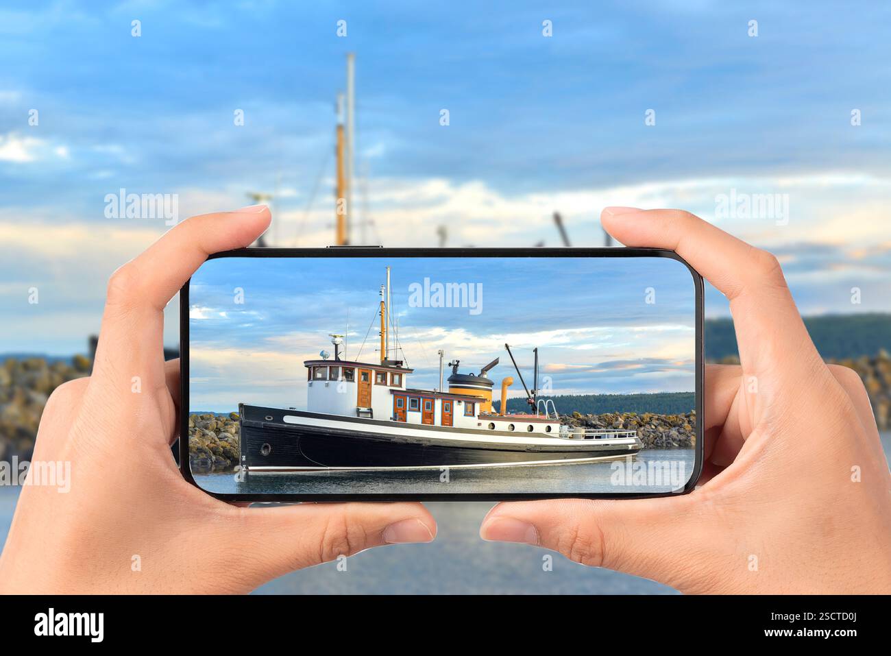 Handy, das ein Foto von einem Boot im Hafen macht Stockfoto