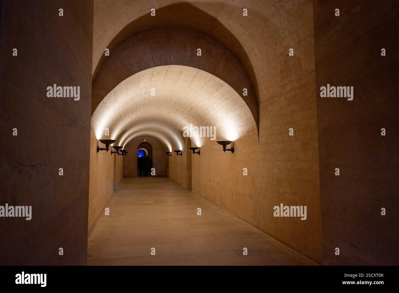 Unterirdischer Krypta-Korridor im Panthéon, Paris, mit Bogendecken, dezenter Beleuchtung und einem geheimnisvollen Ambiente, das zu einer Tür führt Stockfoto