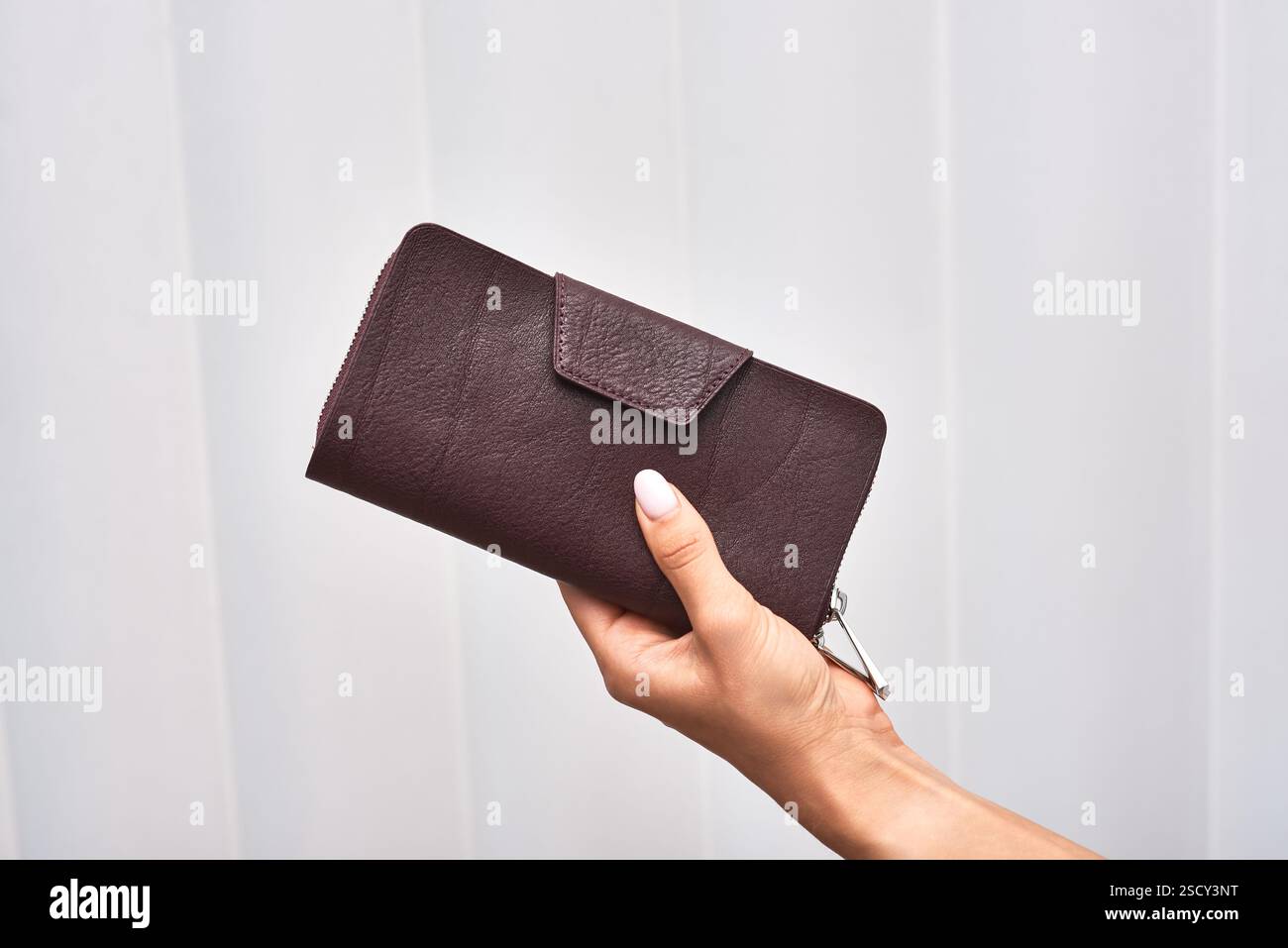 Elegante kastanienbraune Geldbörse mit Verschluss von Hand, ideales stilvolles Accessoire für modebewusste Individuen, das das Konzept der Geldbörse unterstreicht Stockfoto