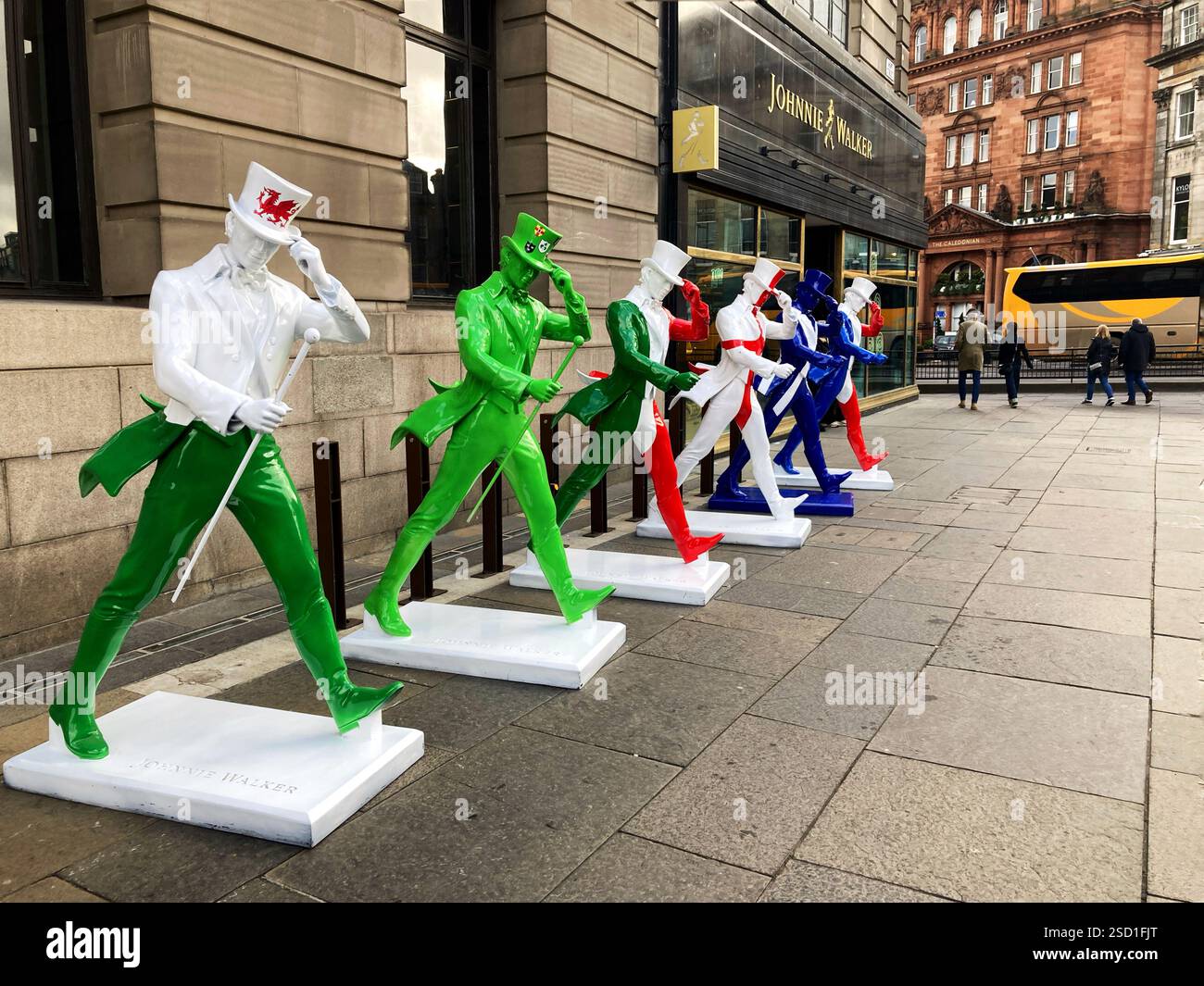 Johnnie Walker Whisky Striding man Statuen in Six Nations Rugby Farben außerhalb der Johnnie Walker Experience, Hope Street, Edinburgh Schottland, 2025 - Smartphone-aufgenommenes Stockfoto