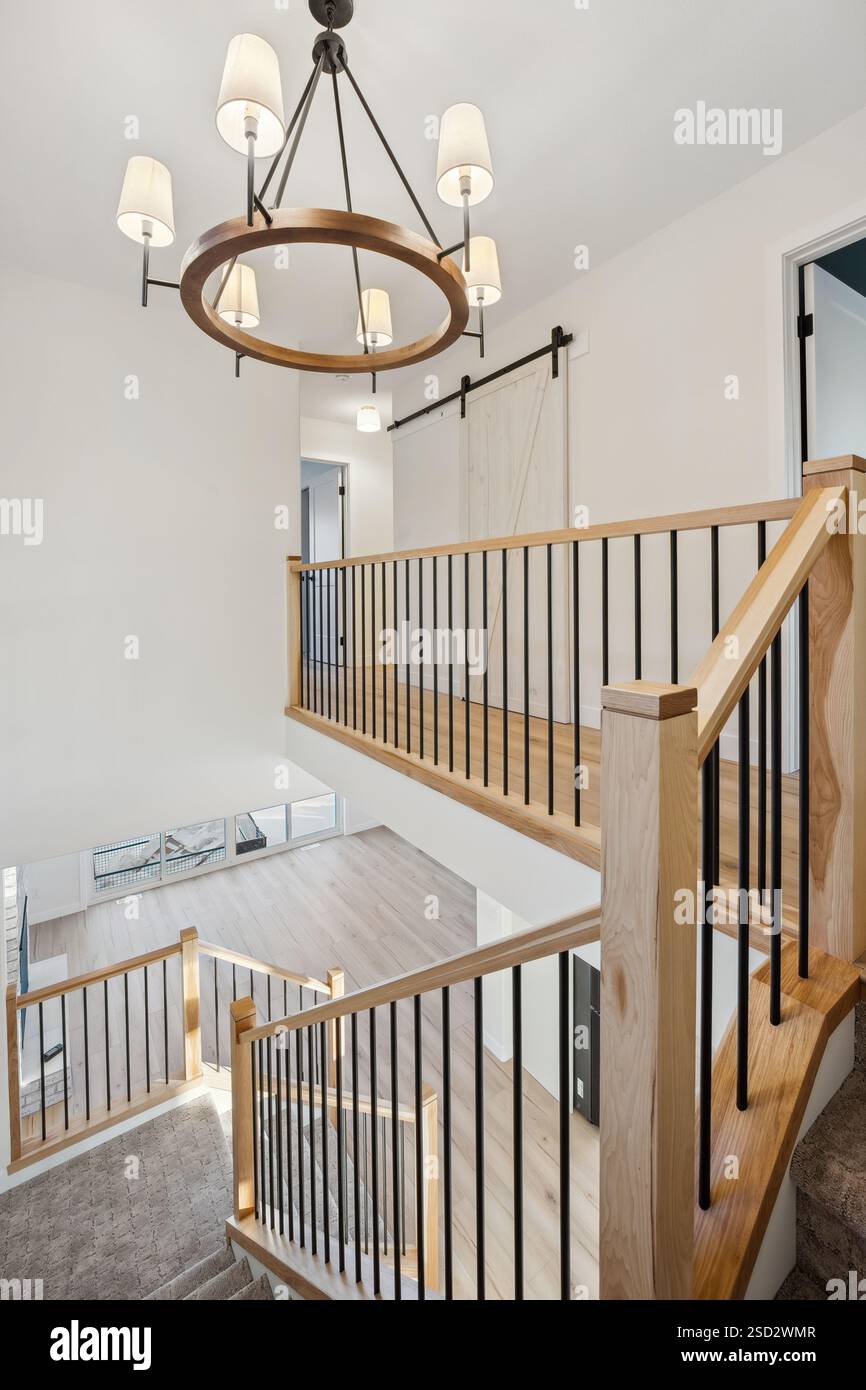 Wendeltreppe mit einem Kronleuchter, der von der Decke hängt. Der Kronleuchter ist aus Holz und hat einen weißen Sockel. Die Treppe befindet sich in einem großen Stockfoto