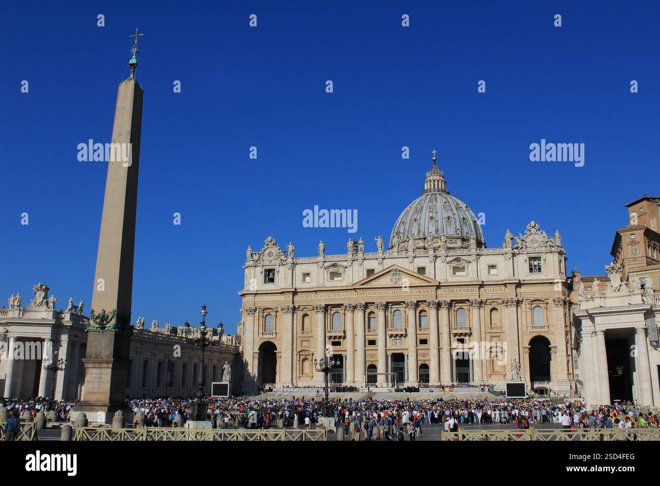 Vatikanstadt - 5. September 2018: Weitwinkelaufnahme des Petersdoms und des Vatikanischen Obelisken an einem sonnigen Tag mit Touristen Stockfoto
