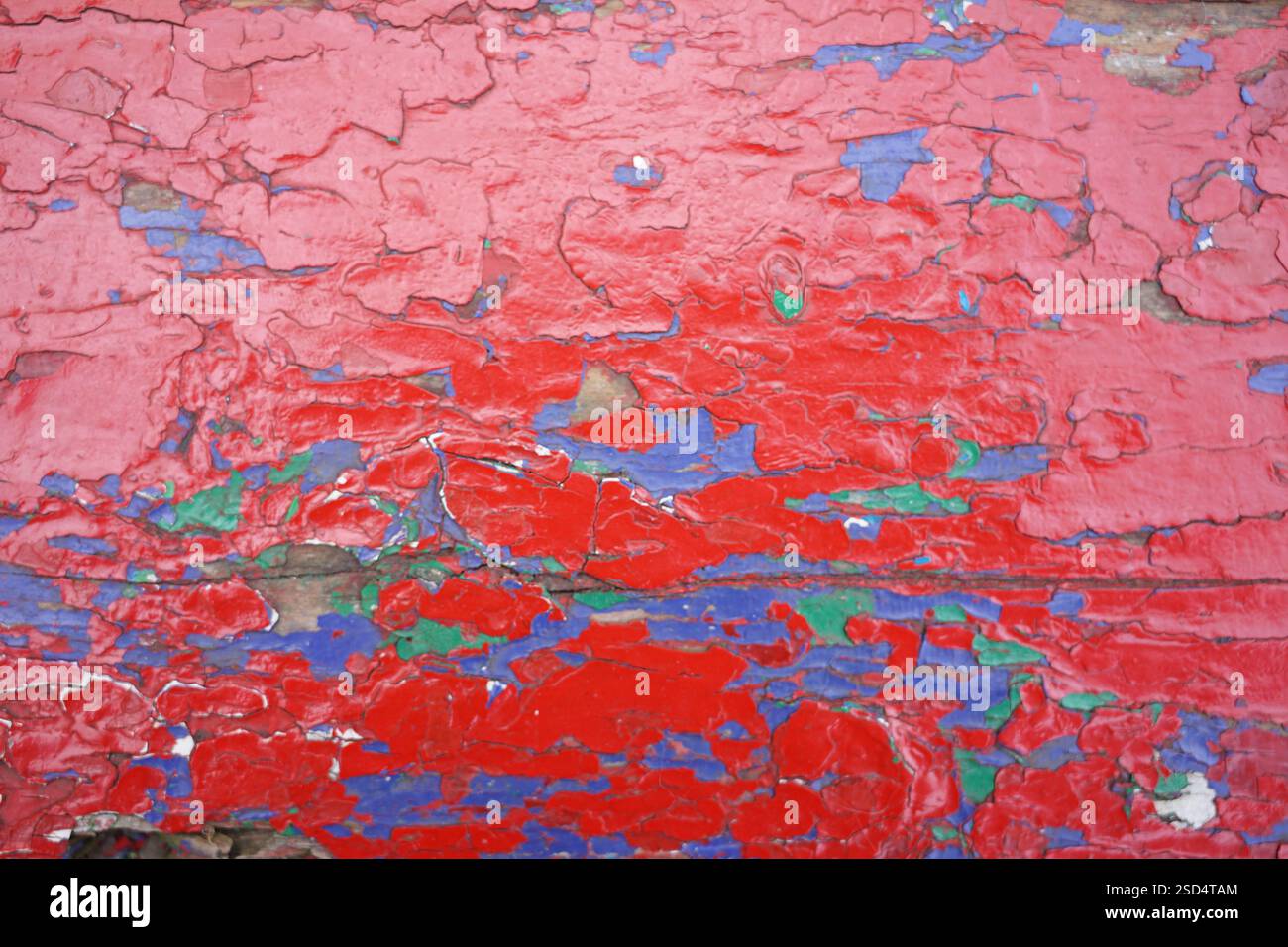 Farben von Rot, Blau und Grün verschmelzen zu einer auffälligen Darstellung abblätternder Farbe auf einer alten Oberfläche. Die Textur vermittelt ein Gefühl von Alter und Geschichte Stockfoto