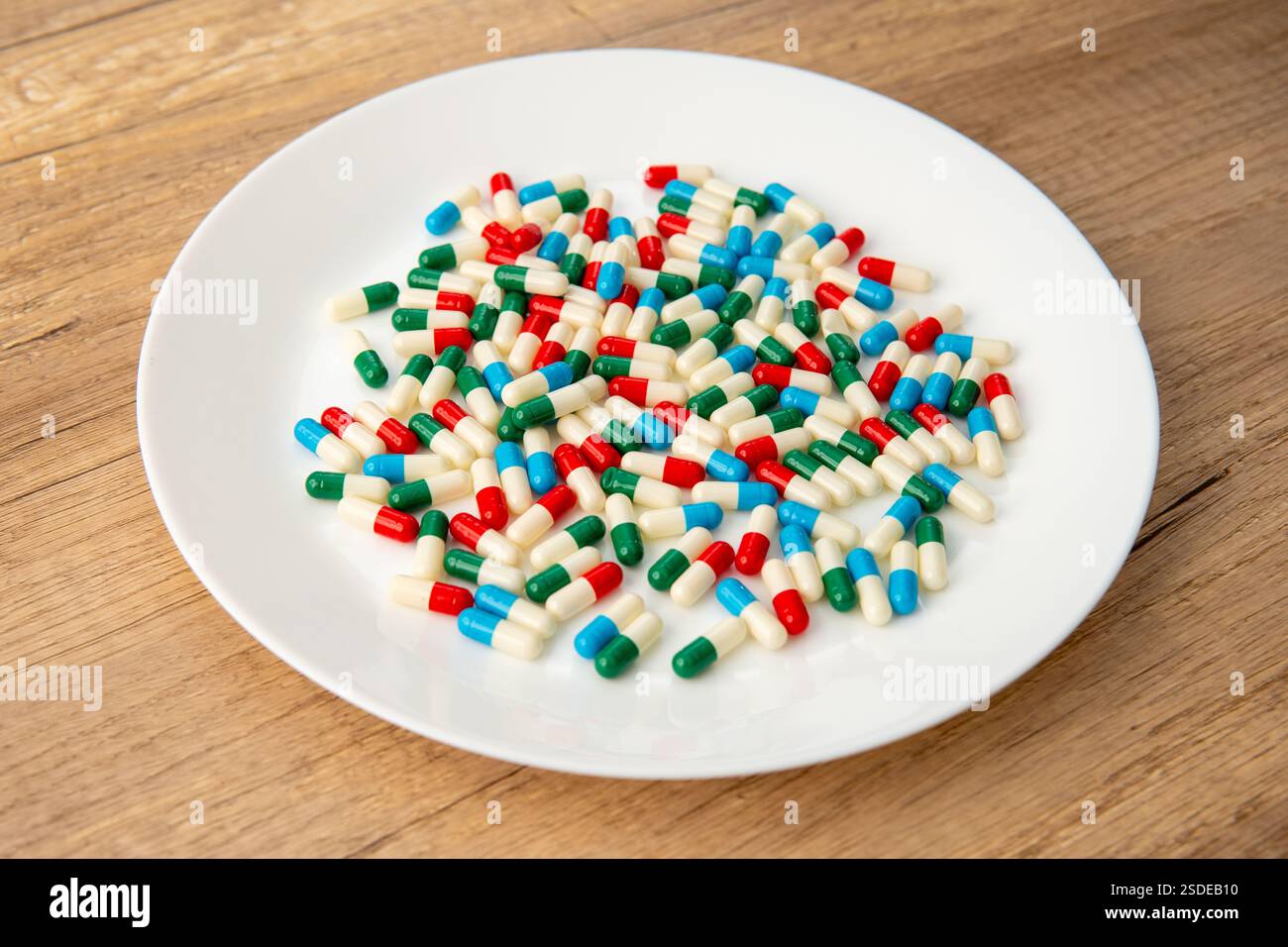 Eine weiße Platte gefüllt mit bunten Kapseln. Medizin- und Gesundheitskonzept. Stockfoto