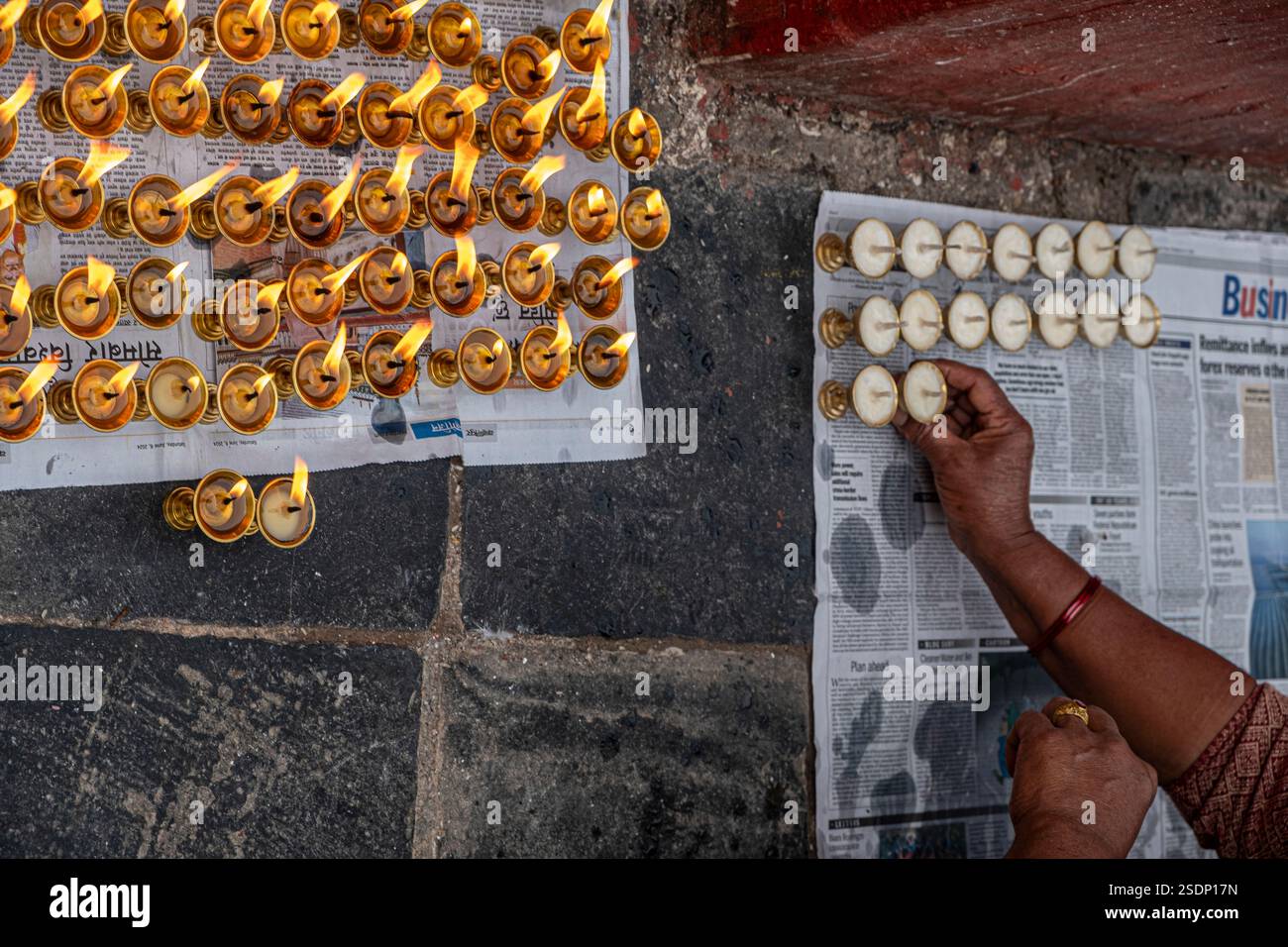 Im ruhigen Herzen von Boudhanath, Kathmandu, setzt eine Person sorgfältig Kerzen in ordentliche Reihen. Stockfoto
