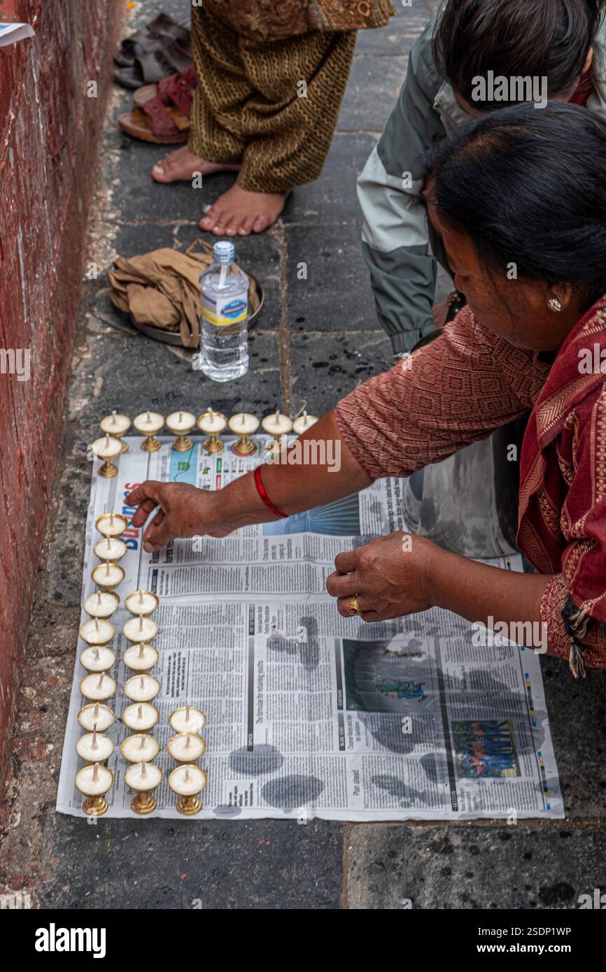 Im ruhigen Herzen von Boudhanath, Kathmandu, setzt eine Person sorgfältig Kerzen in ordentliche Reihen. Stockfoto